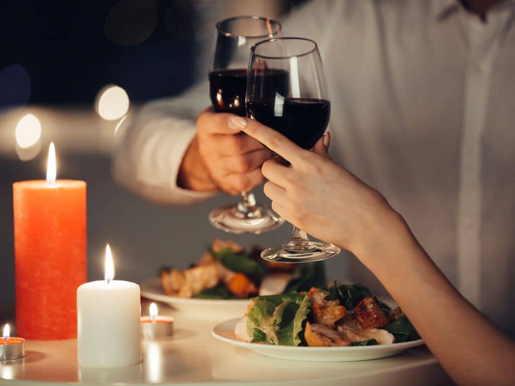 Couple toasting wine during a romantic candlelight dinner in Ahmedabad.