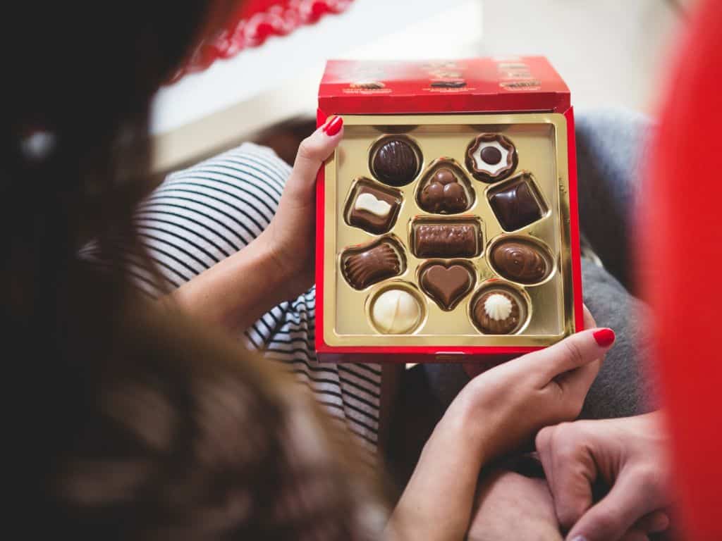 Two people sharing a premium box of assorted chocolates, a popular rakhi gift idea under ₹500 in Ahmedabad from Escape Zone