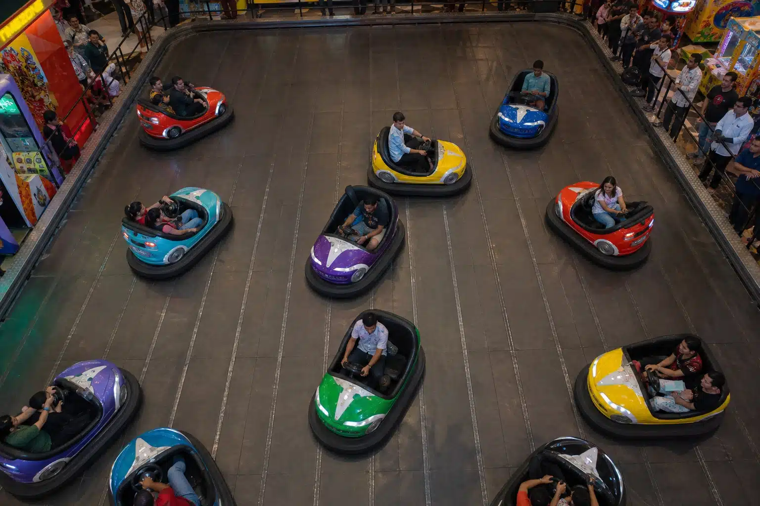 People riding bumper cars in a mall game zone.