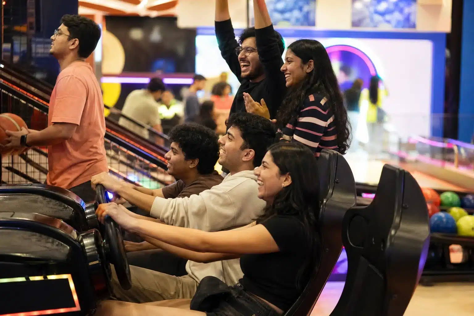 Friends playing arcade games at a mall arcade.
